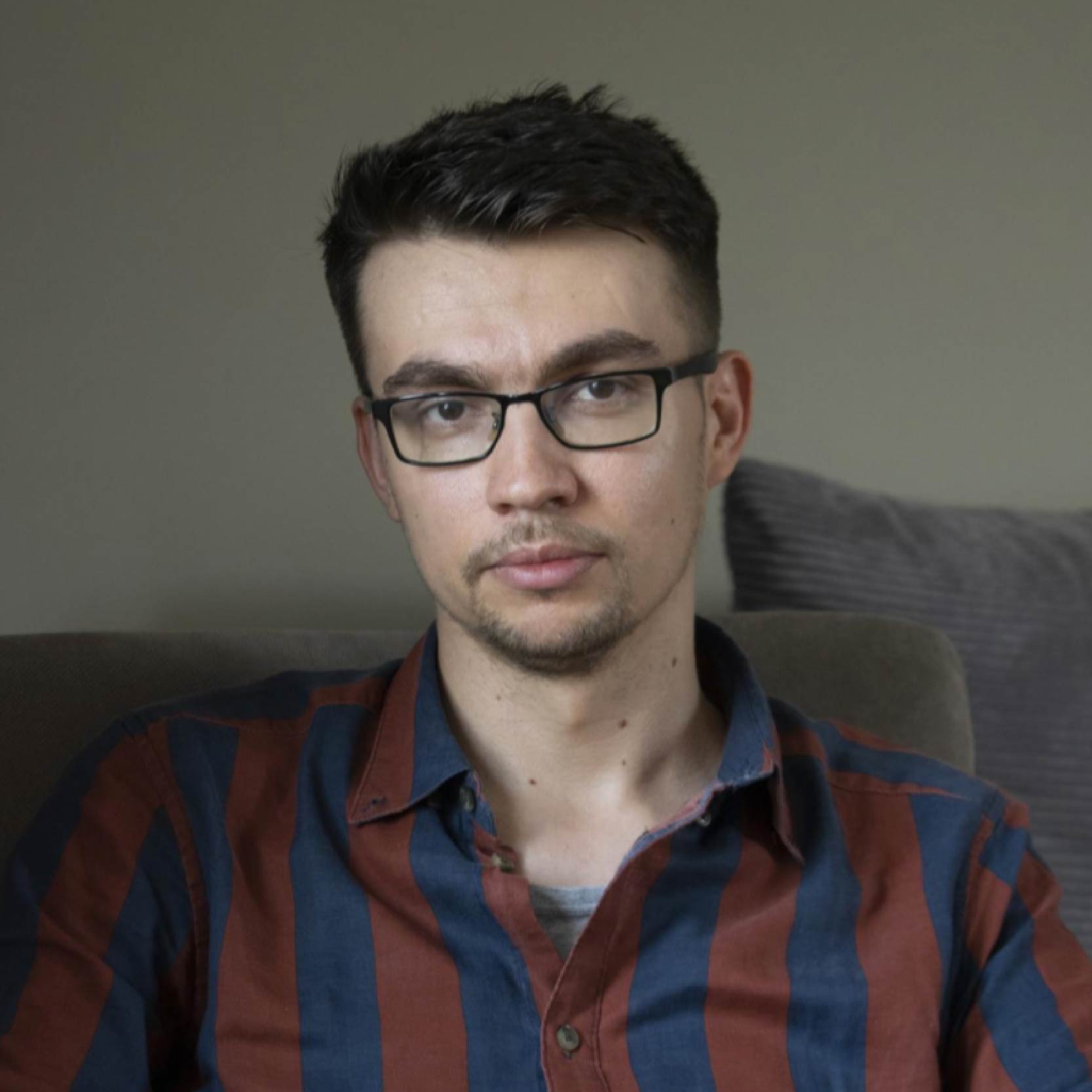 Portrait photo of Krzysztof Bielski, PhD student, wearing glasses and a navy and brown striped shirt.