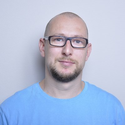 Portrait photo of Prof. Szymon Wichary, head of the research team, wearing a blue T-shirt and black glasses.